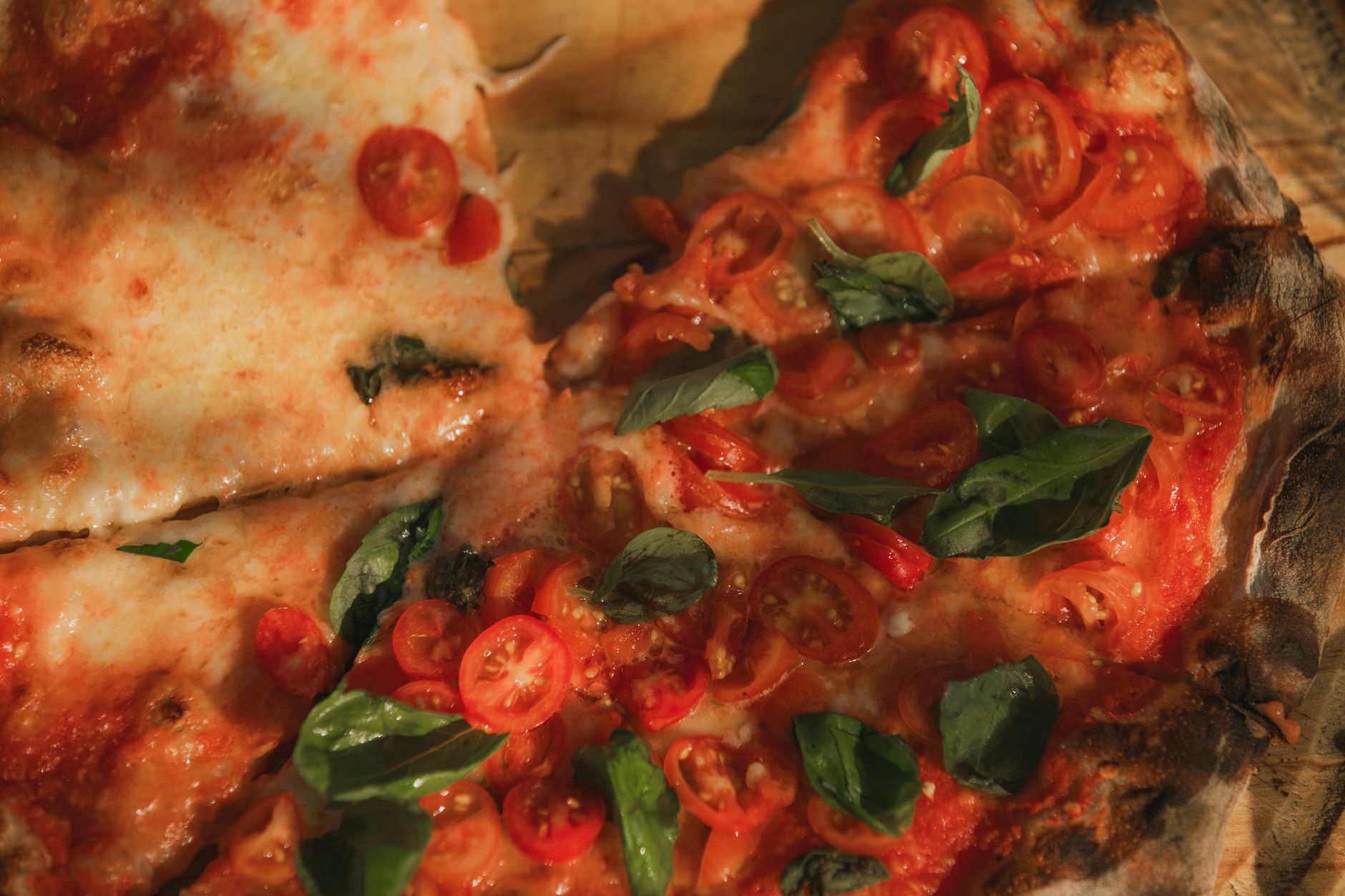Top view of a baked Margherita pizza with cherry tomatoes, mozzarella and basil