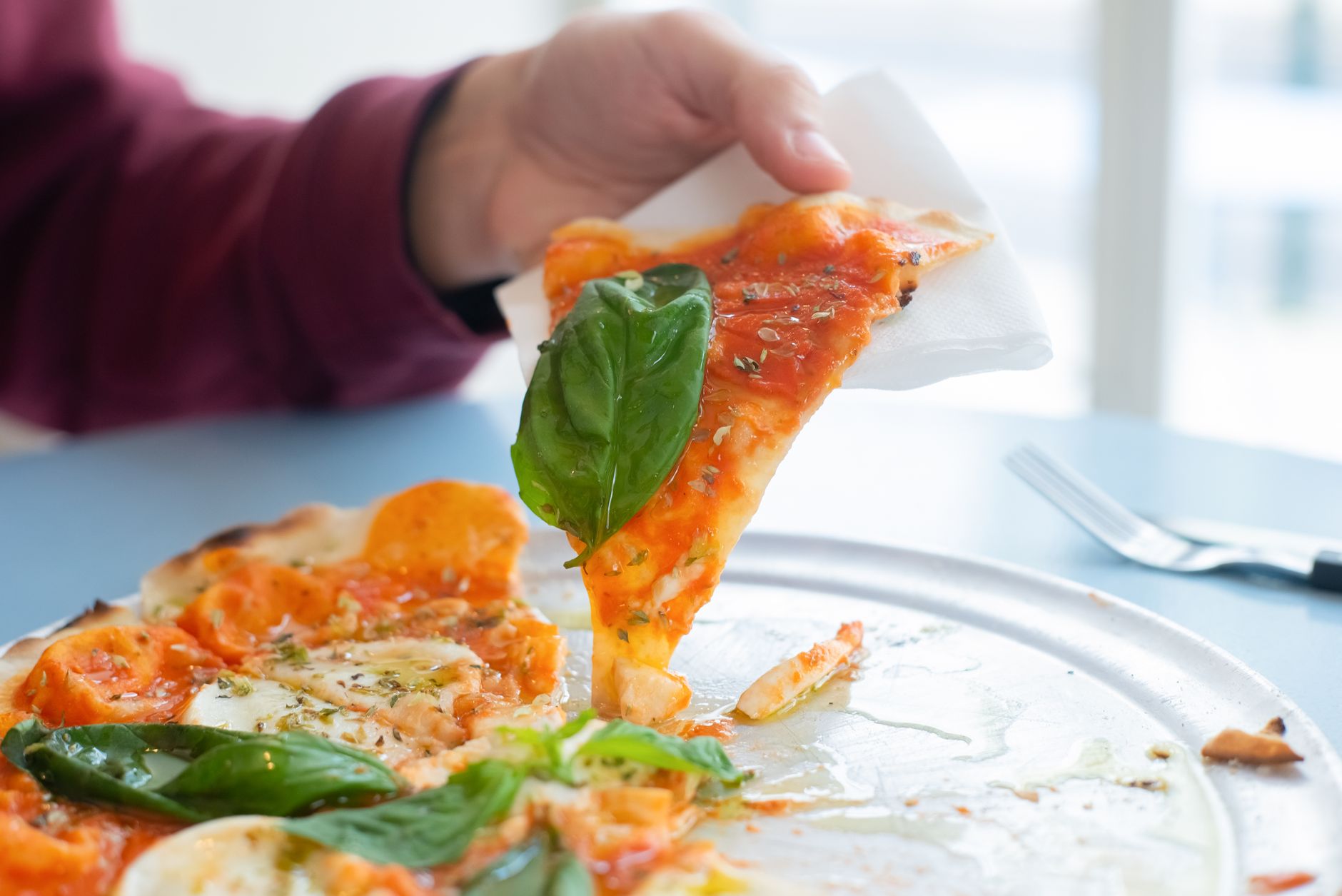 Hand holding a single slice of pizza