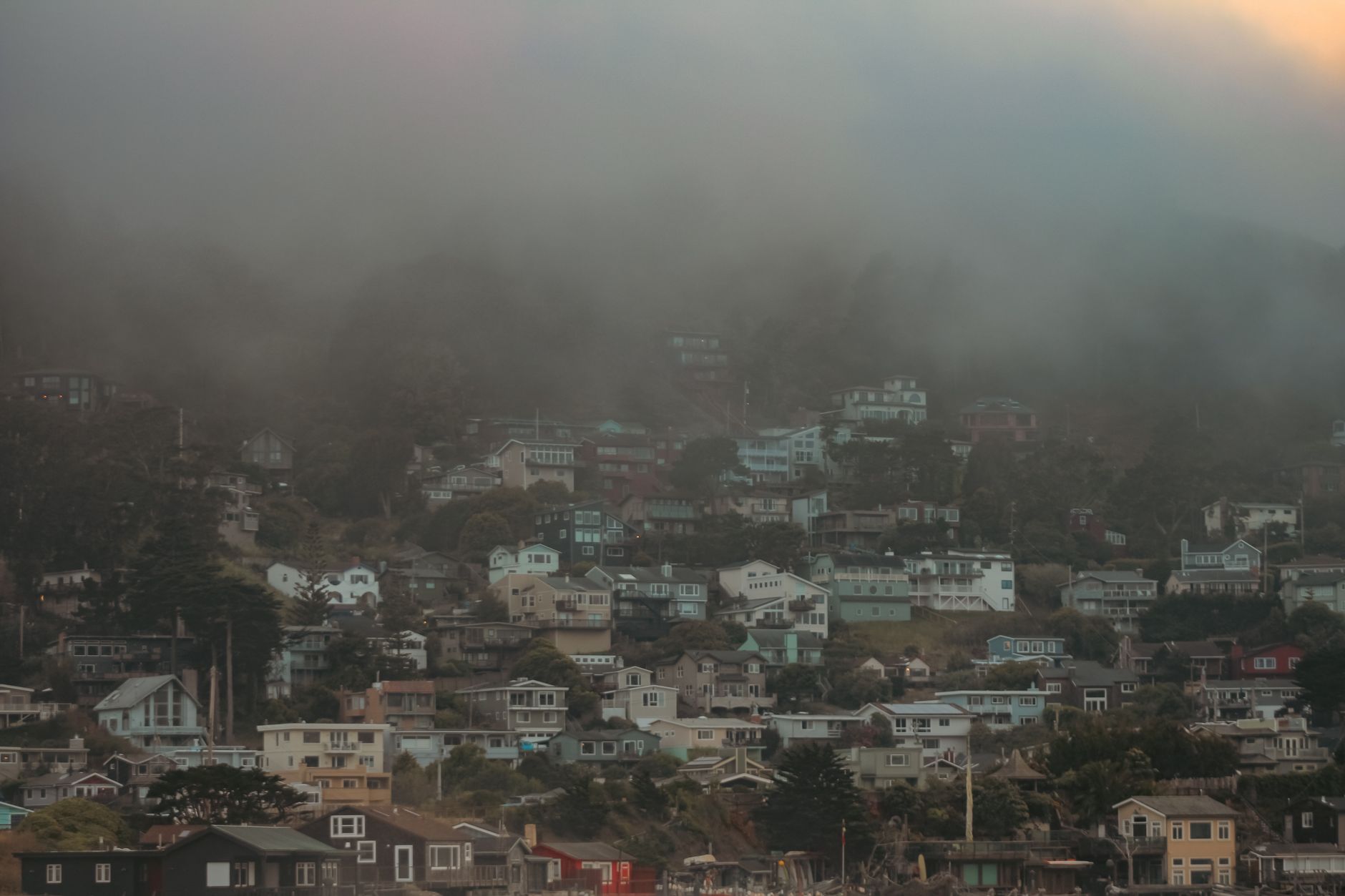 Aerial view of a misty San Francisco-style hillside neighborhood in fog