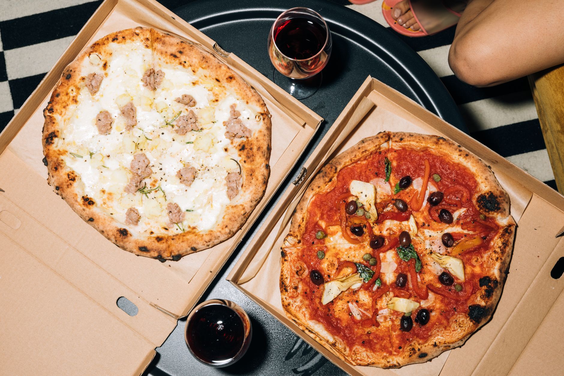 Two pizzas in open boxes set out for a group meal