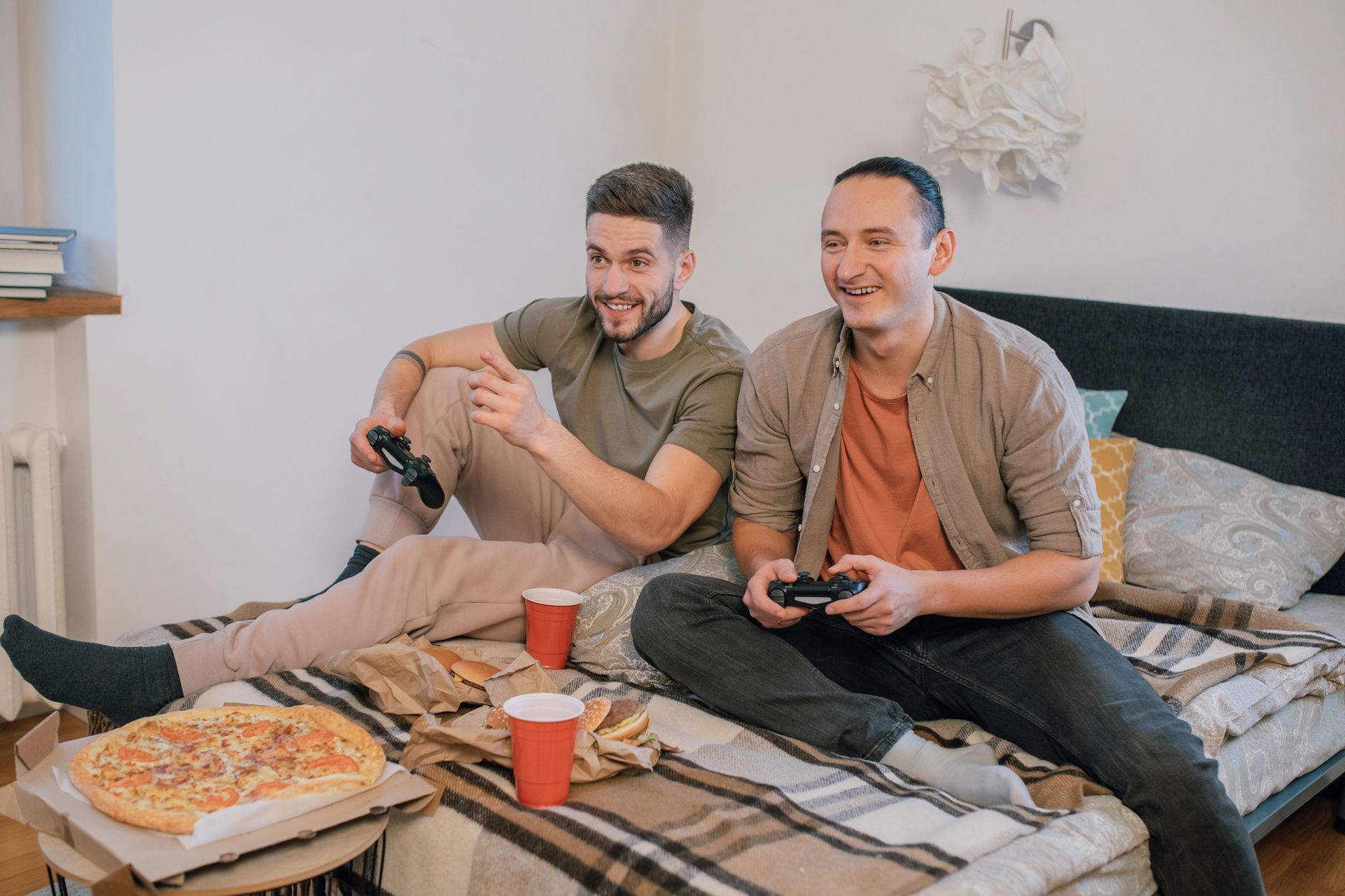 Friends playing video games and eating pizza together at a watch party