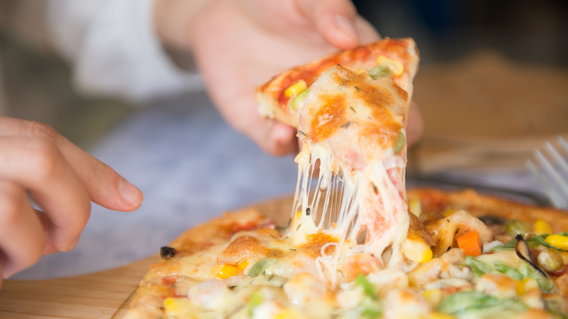 Close-up of a cheesy pizza slice being pulled from the pie
