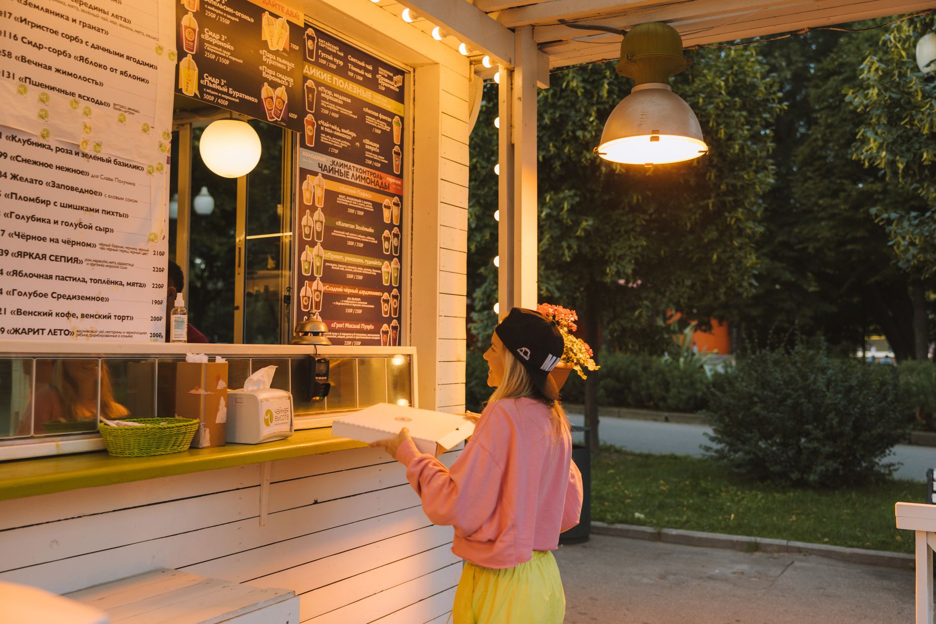 Woman collecting her pizza order at an outdoor food stall in the evening