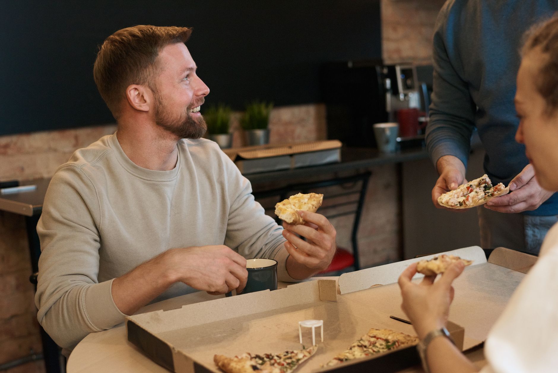 Group of coworkers sharing pizza together indoors