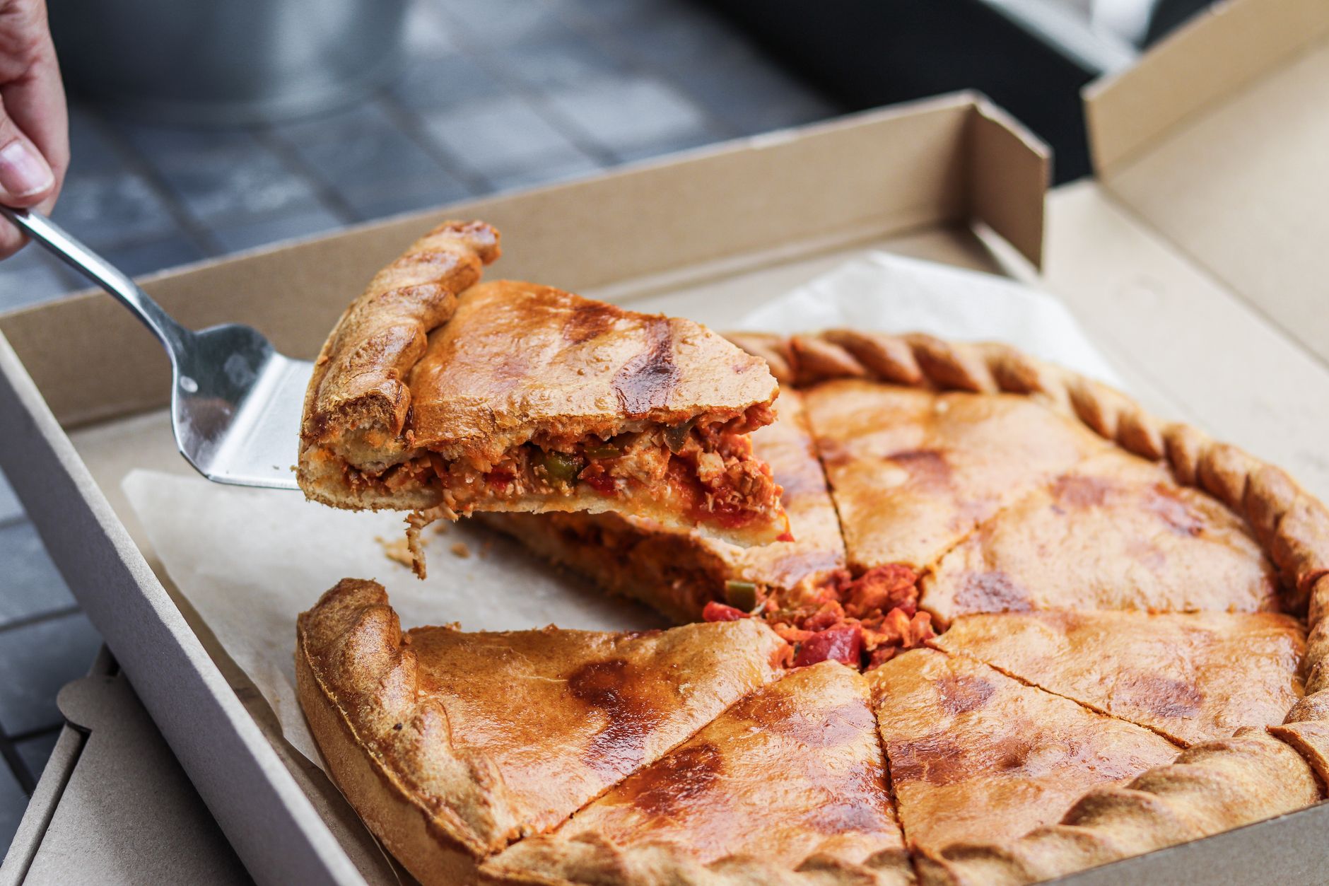 Deep-dish pizza slice being served from a box
