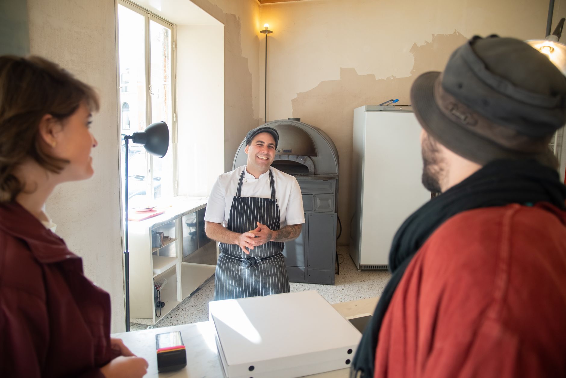 Pizzeria chef talking with customers at the counter