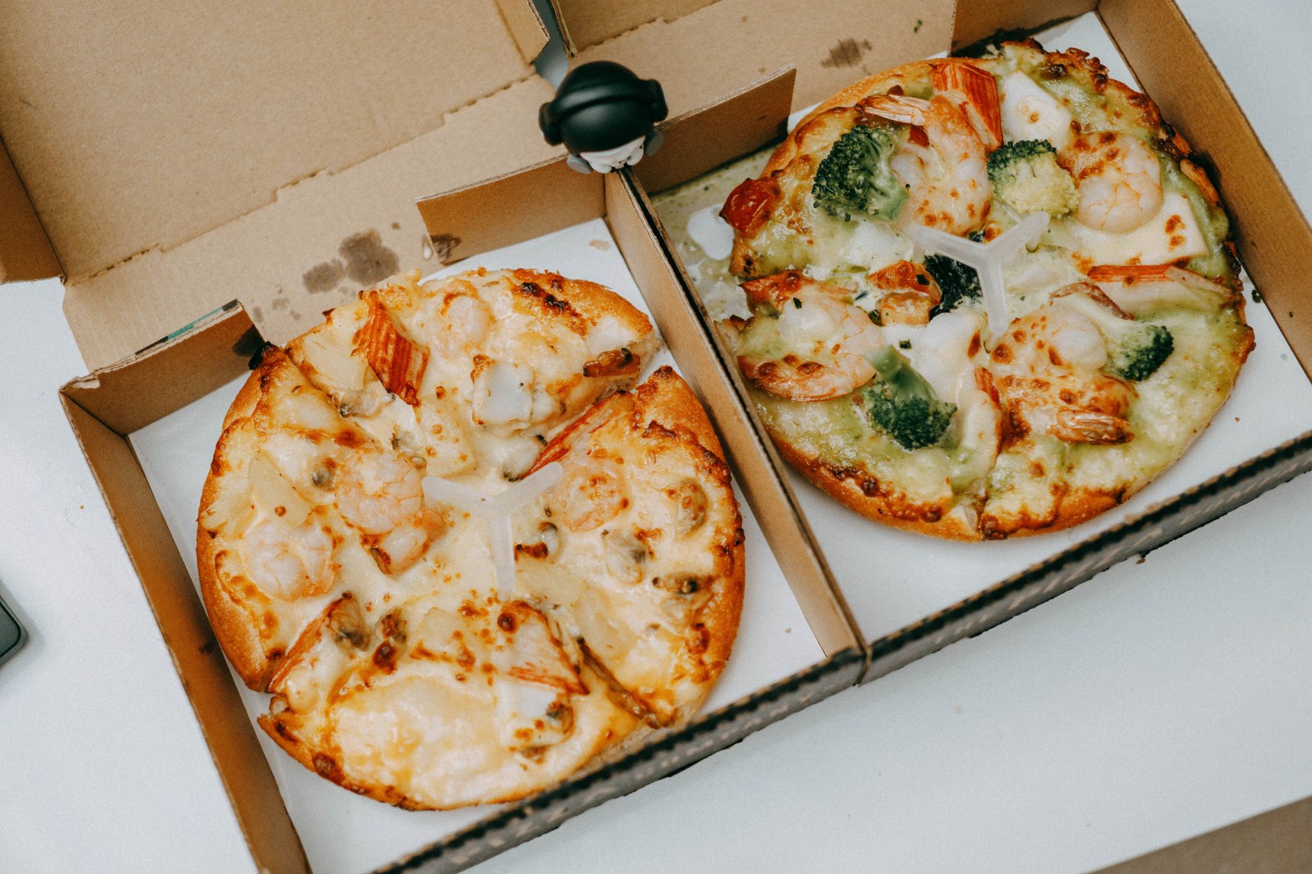 Open pizza delivery boxes with whole pies ready to be picked up