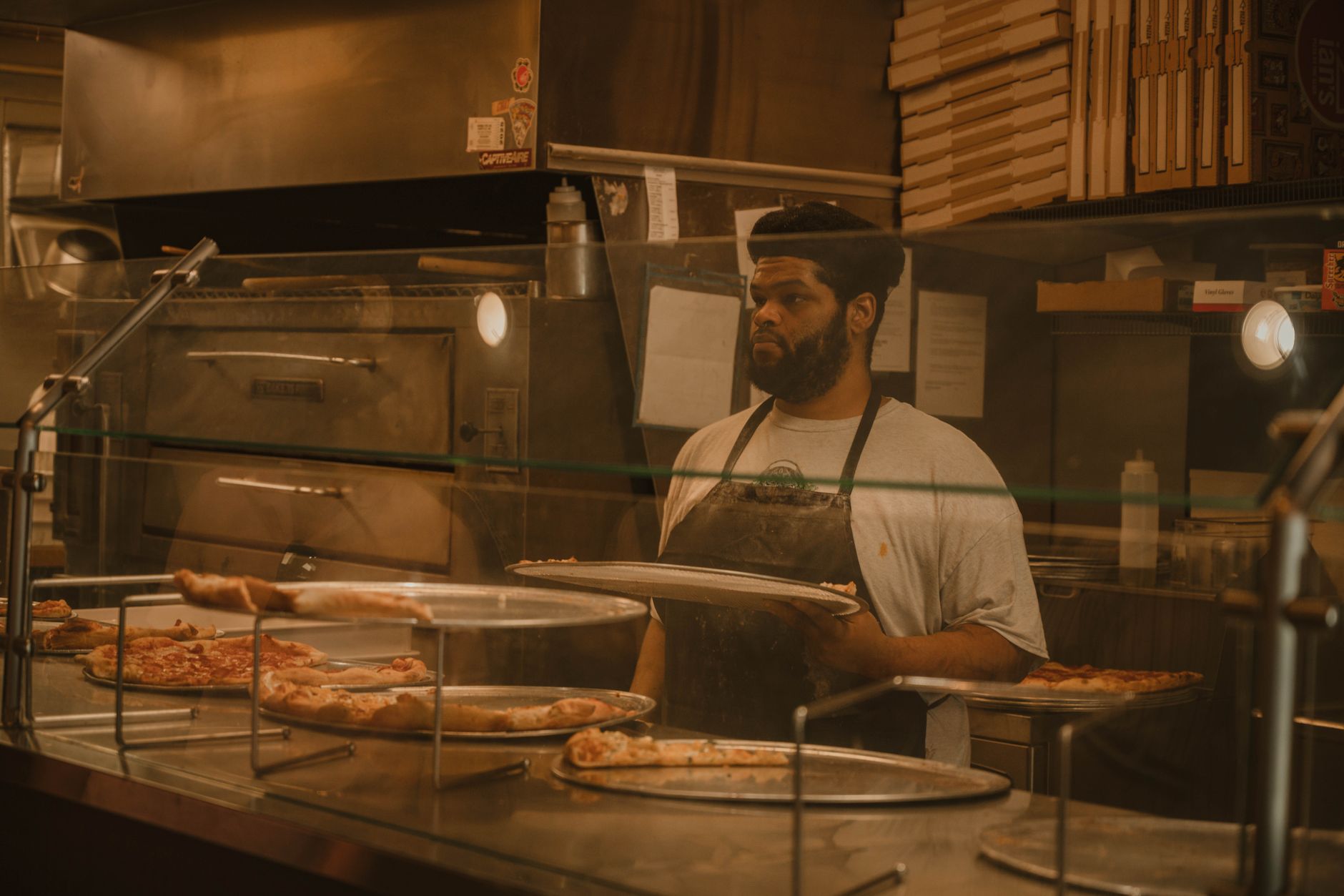 Pizza chef serving fresh slices at a pizzeria counter